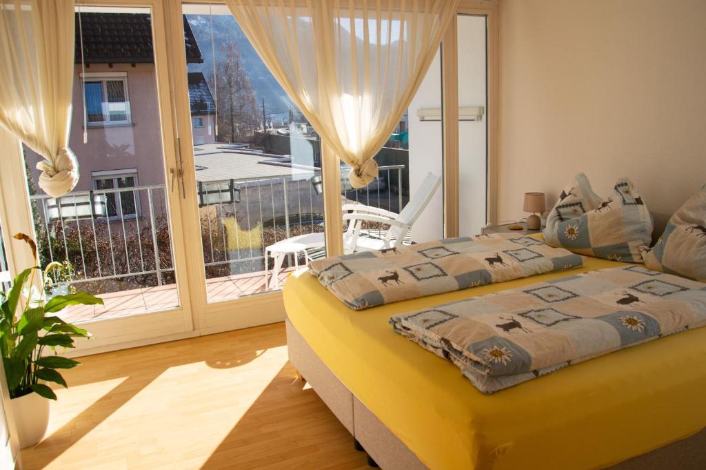 a bedroom with a yellow bed and a balcony at Private doublebed Room with balcony in shared house in Dornbirn