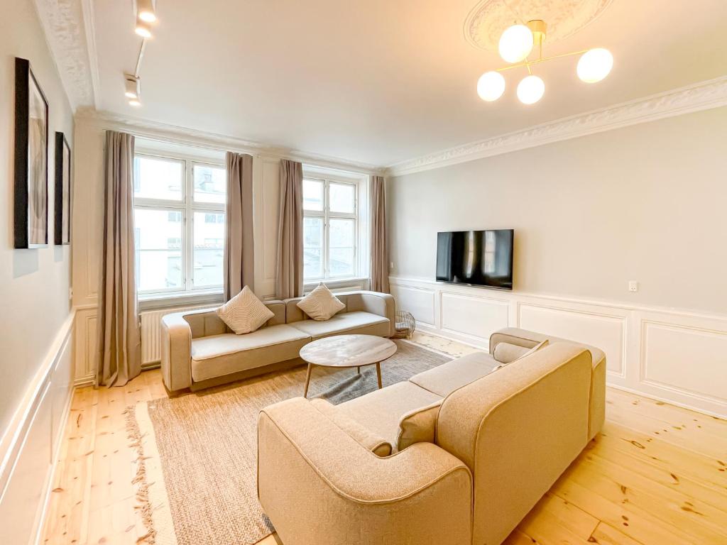 a living room with two couches and a tv at Big 4 BR Flat with Bathtub by CPH City Hall Square in Copenhagen