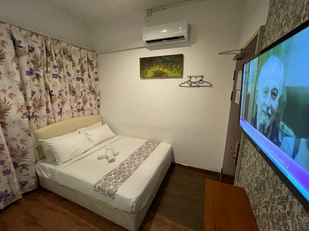 a bedroom with a bed and a flat screen tv at Woodpecker Lodge, Kuching in Kuching
