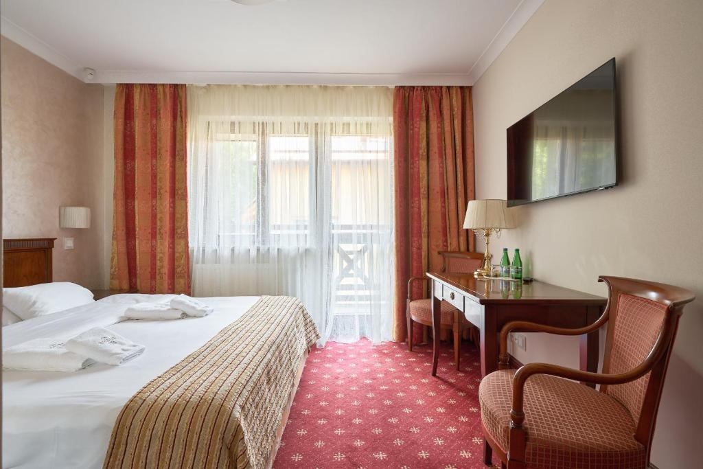 カルパチにあるWoźniak Residenceのベッド2台、デスク、窓が備わるホテルルームです。