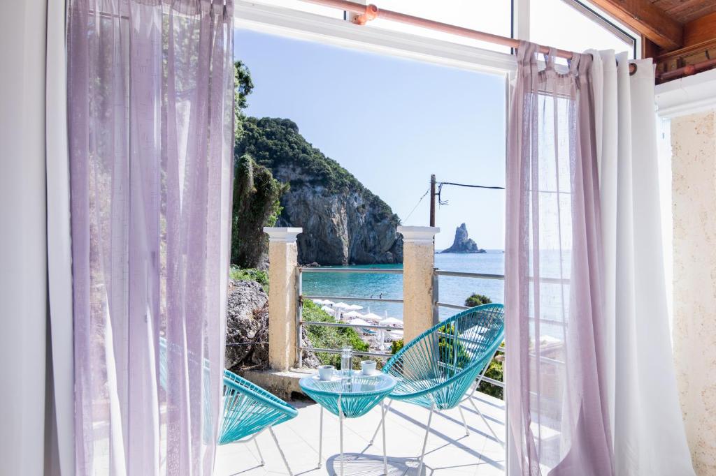 a room with a view of the ocean from a balcony at Agios Gordios Ammos House in Agios Gordios