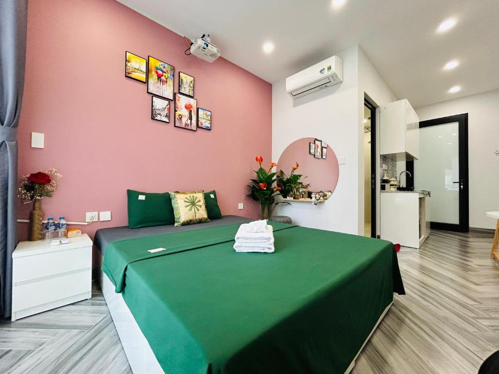a bedroom with a green bed with a pink wall at Godidi Homestay&Apartment ( Westlake ) in Hanoi