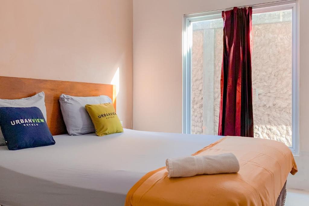 ein Schlafzimmer mit einem großen Bett mit Kissen und einem Fenster in der Unterkunft Urbanview Hotel AVA Banjarmasin by RedDoorz in Banjarmasin