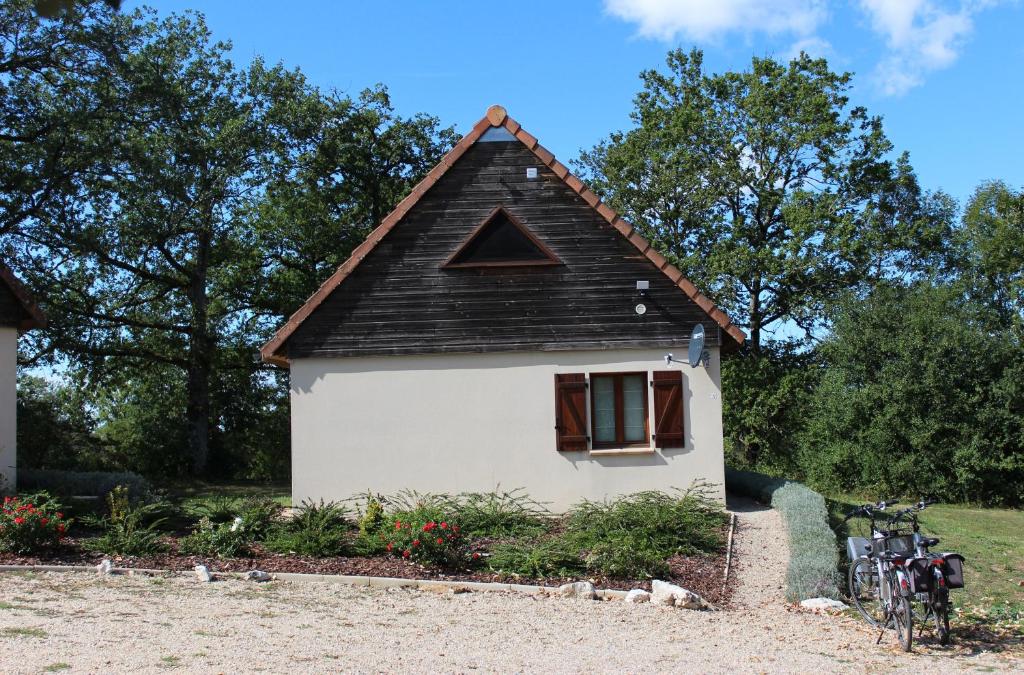 une petite maison blanche avec un toit noir dans l'établissement Le Lac Bleu huis 17, à Lacapelle-Marival