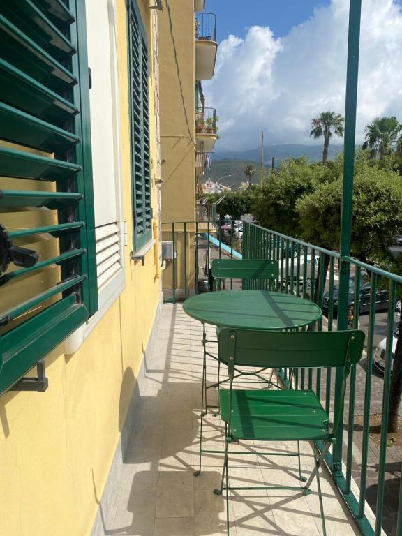 un balcón con mesas verdes y sillas en un edificio en Casa Gaeta, en Gaeta