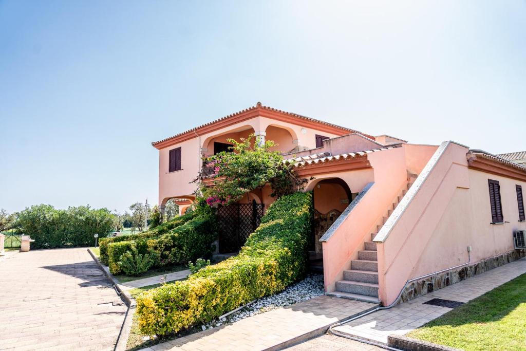 a pink house with a staircase and bushes at Sardegnadream in San Teodoro