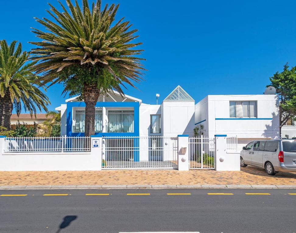 a white house with a palm tree in front of it at Ocean Way Villas - Self Catering in Cape Town