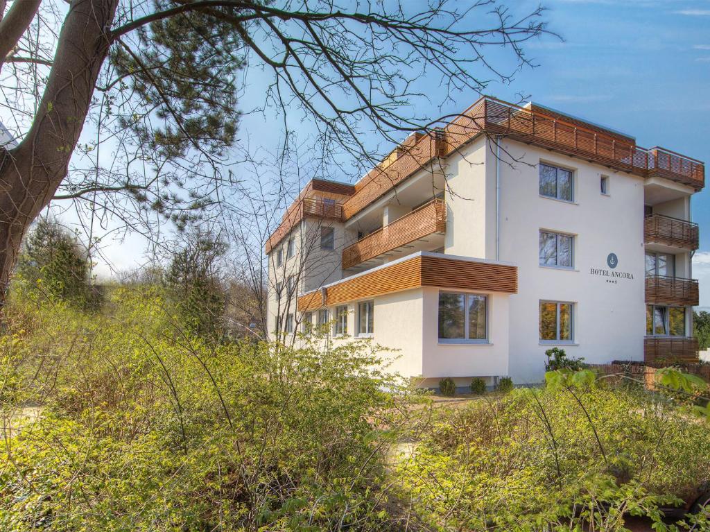 biały budynek na szczycie wzgórza z drzewami w obiekcie Hotel Ancora w mieście Timmendorfer Strand