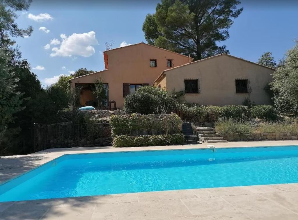 a villa with a swimming pool in front of a house at Villa Les Agrions avec piscine in Le Thoronet