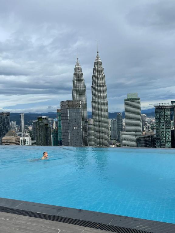 un hombre nadando en una piscina con un perfil urbano en KLCC Platinum 2 by Hibernate en Kuala Lumpur