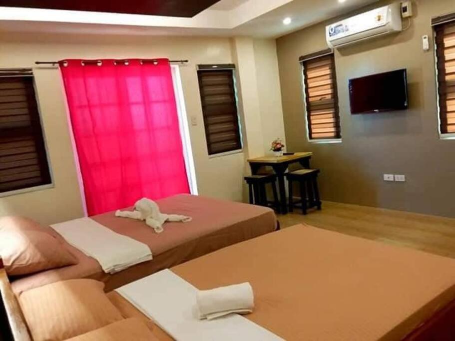 a room with two beds and a pink curtain at Marino Transient 4 rooms in Alaminos