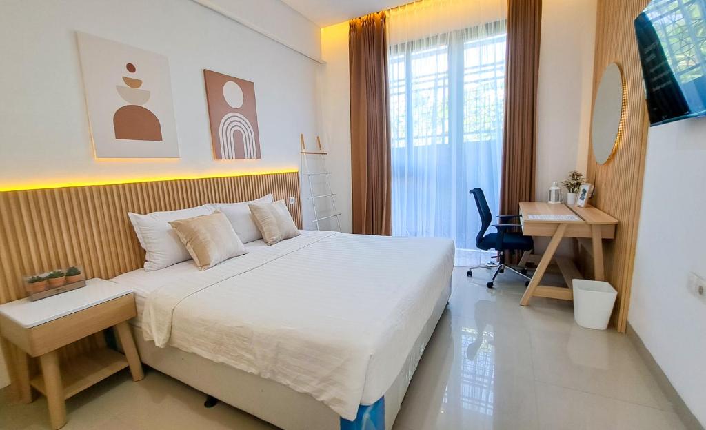 a bedroom with a large bed and a desk in it at Olivia SOHO Guest House in Legian