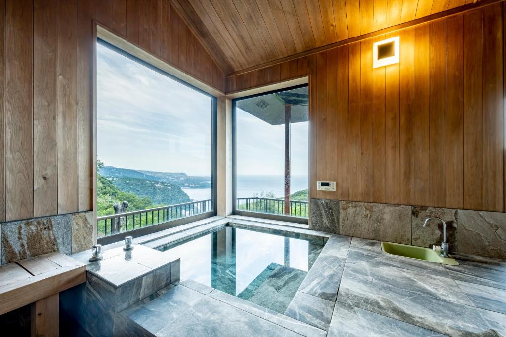 ein Bad mit einem Pool und einem großen Fenster in der Unterkunft プライベートリゾート碧海 in Okawa