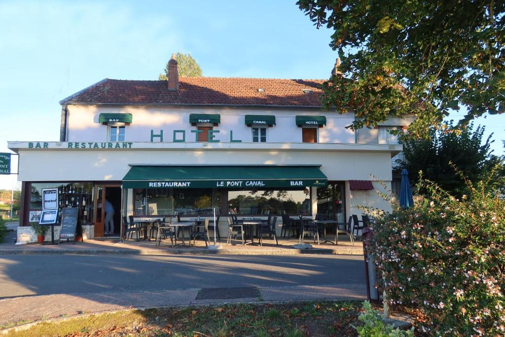 a building with tables and chairs in front of it at Auberge du pont canal in Briare