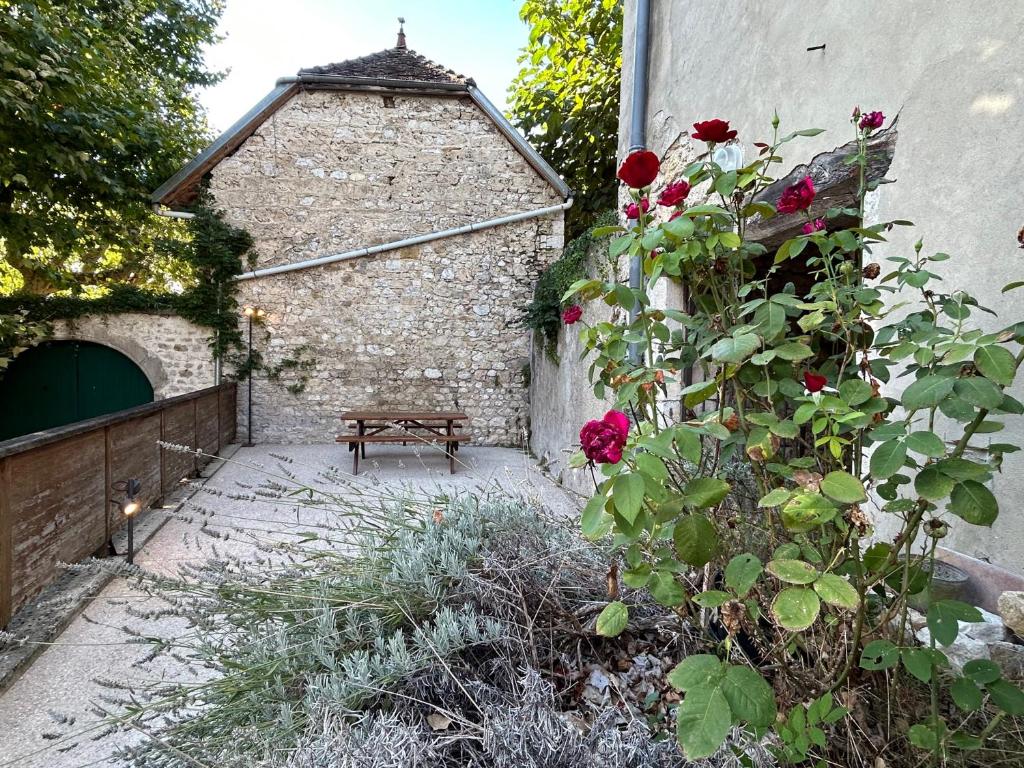 einen Garten mit einer Bank neben einem Backsteingebäude in der Unterkunft Gite Au pied du Grand Colombier in Talissieu