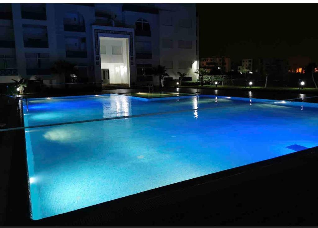 una gran piscina por la noche con iluminación azul en Ryad martil en Martil