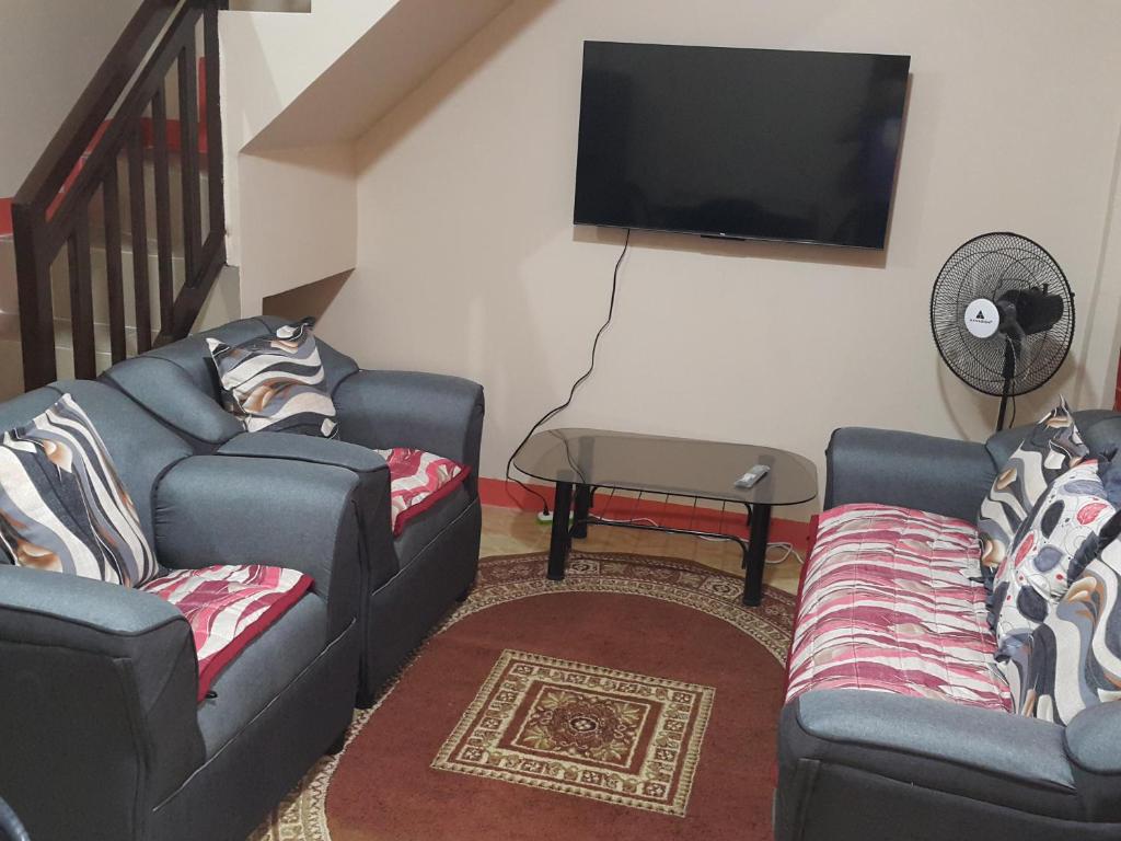 ein Wohnzimmer mit 2 Sofas und einem Flachbild-TV in der Unterkunft Eve's Place Transient Apartment in Tanay