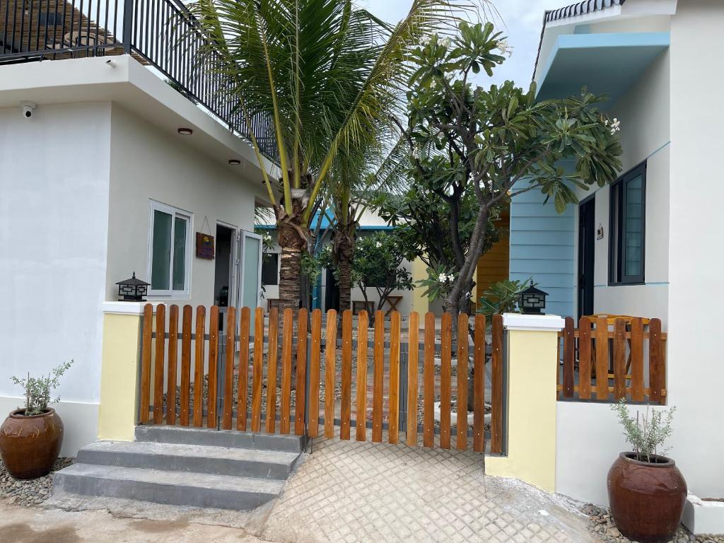 a wooden fence in front of a house with palm trees at Color Inn - Homestay & Cafe in Ninh Hải