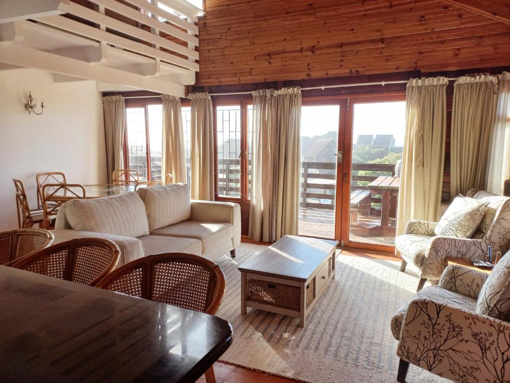 un soggiorno con divani, tavolo e finestre di The beach cabin with pool a Port Alfred