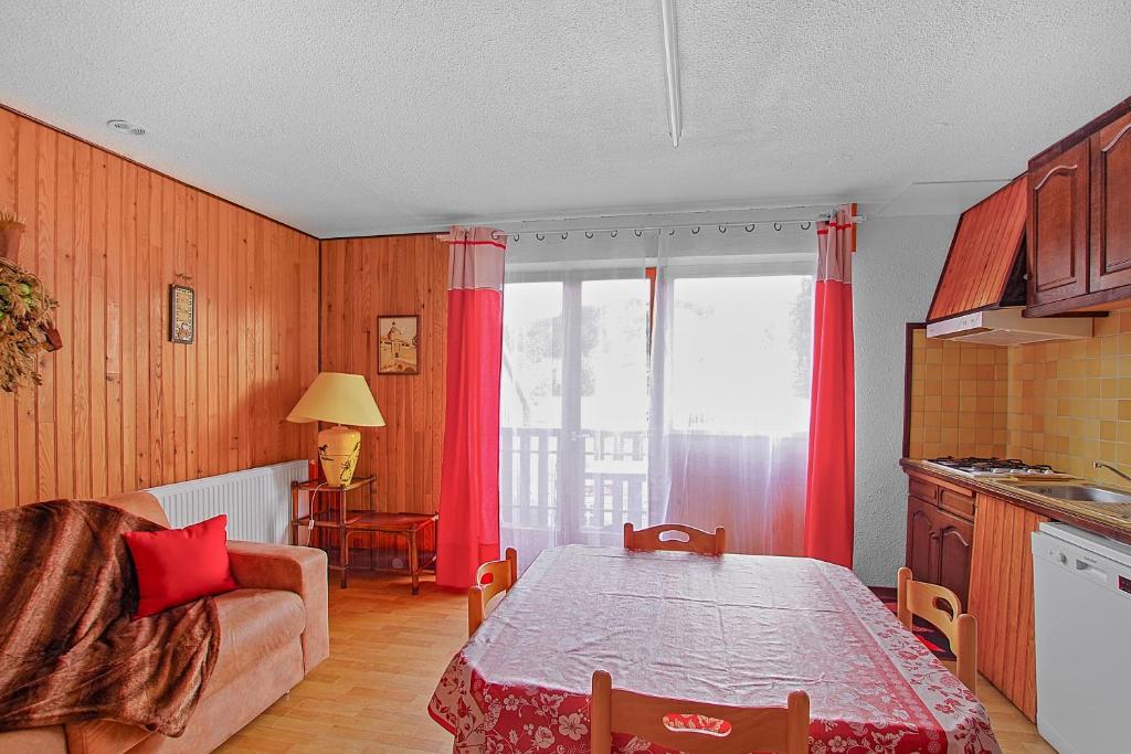 a kitchen with a table and red curtains in a room at Appartement CERF in La Llagonne