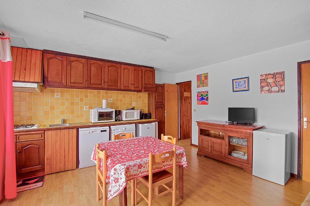 a kitchen with wooden cabinets and a table with a table cloth at Appartement CERF in La Llagonne