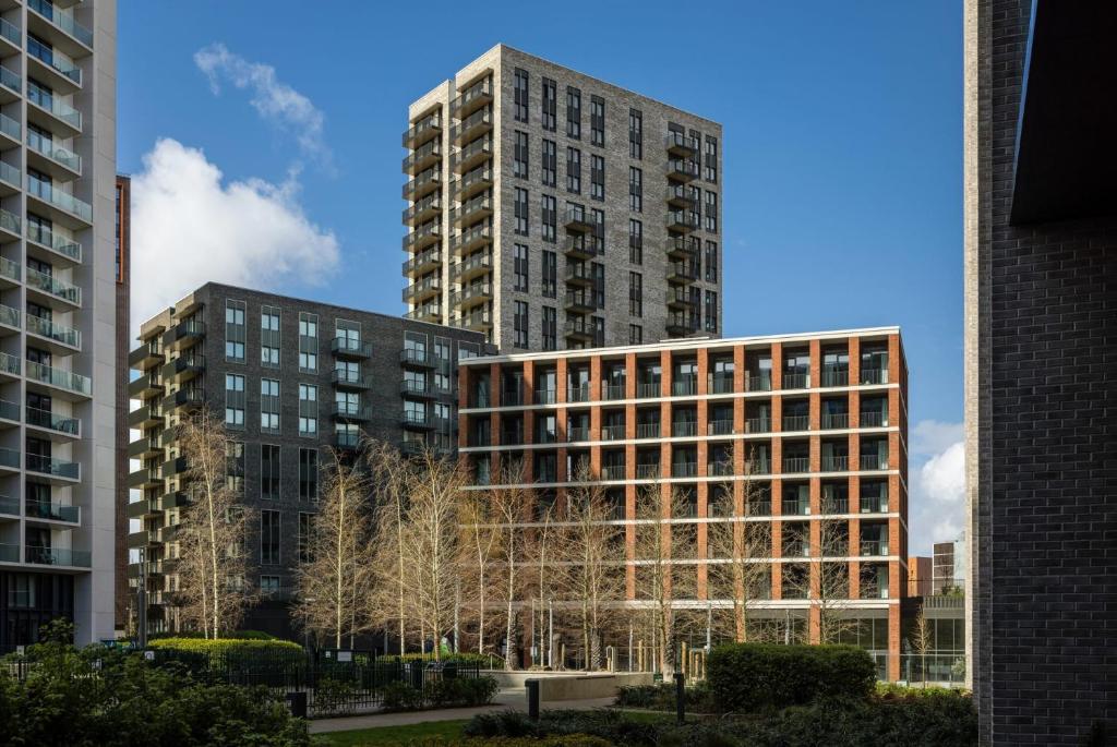 zwei hohe Gebäude mit Bäumen davor in der Unterkunft Botanical-inspired apartments at Repton Gardens right in the heart of Wembley Park in London