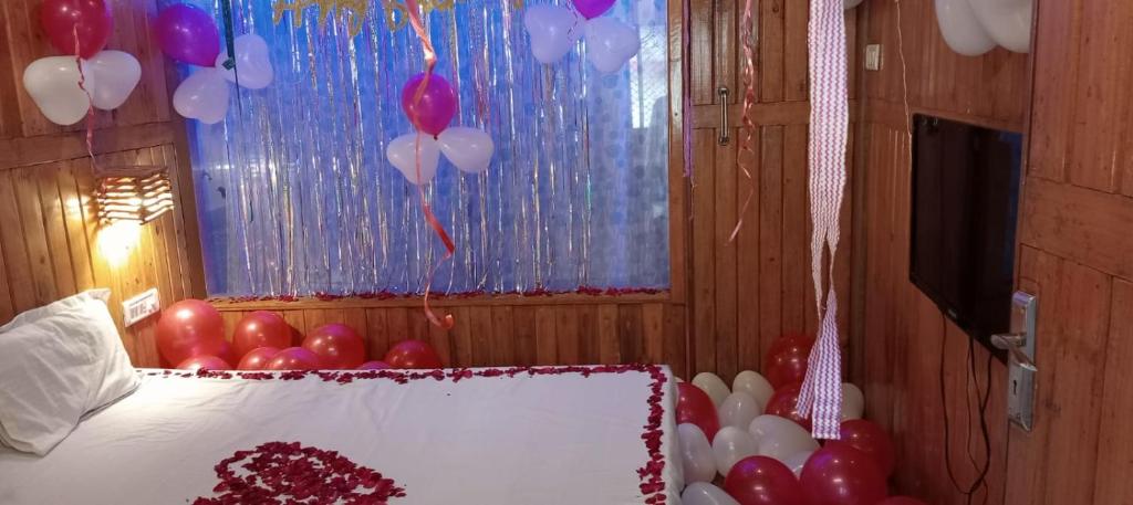 a room with balloons and a bed with a cake at Altaf's motel in Matheran