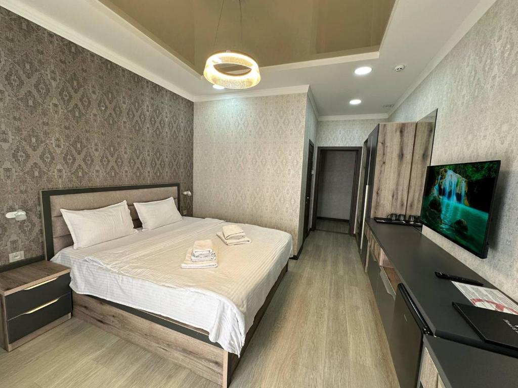 um quarto com uma cama e uma televisão de ecrã plano em VIP Hotel em Tashkent
