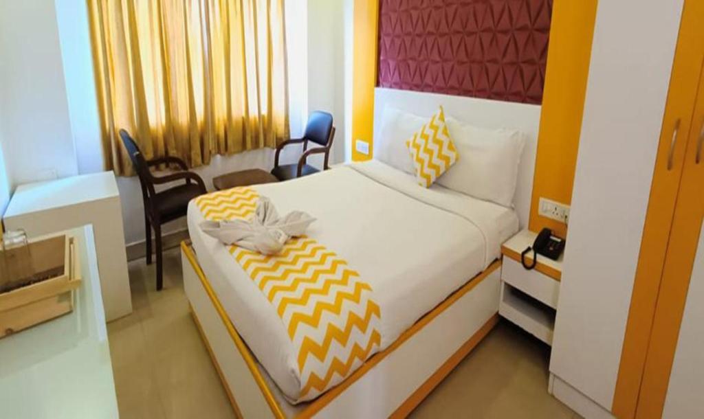 ein Schlafzimmer mit einem Bett und Stühlen in einem Zimmer in der Unterkunft FabHotel Prime Stalin Pleasant Park in Chennai