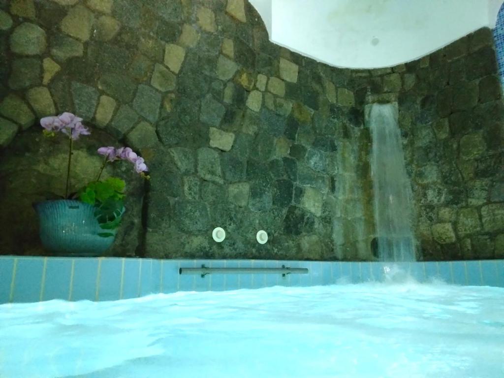 a swimming pool with a waterfall in a stone wall at Hotel Villa Angelica in Ischia