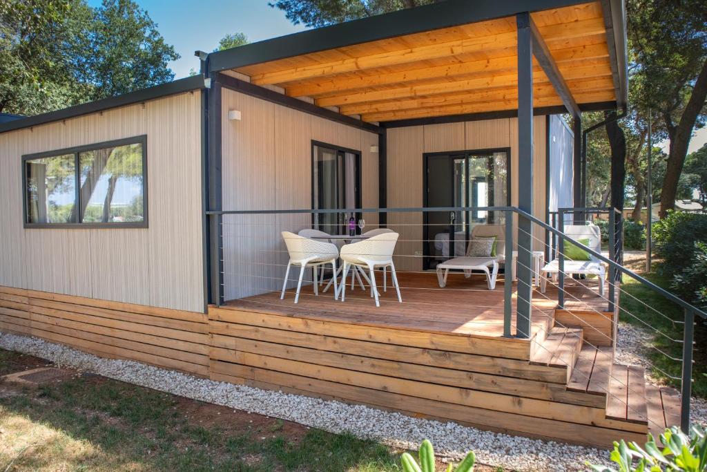 a tiny house with a deck with a table and chairs at Arena Stoja Camping Homes in Pula