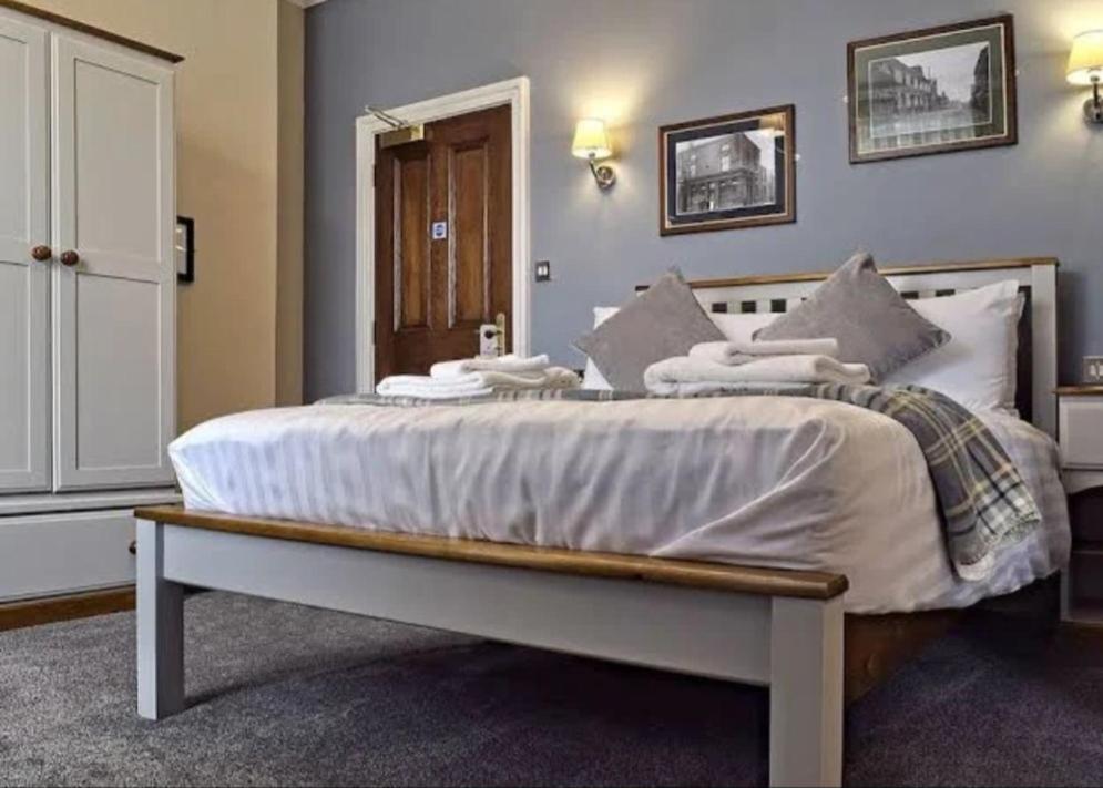 a bedroom with a large bed with white sheets and pillows at The Seven Stars in Stourbridge