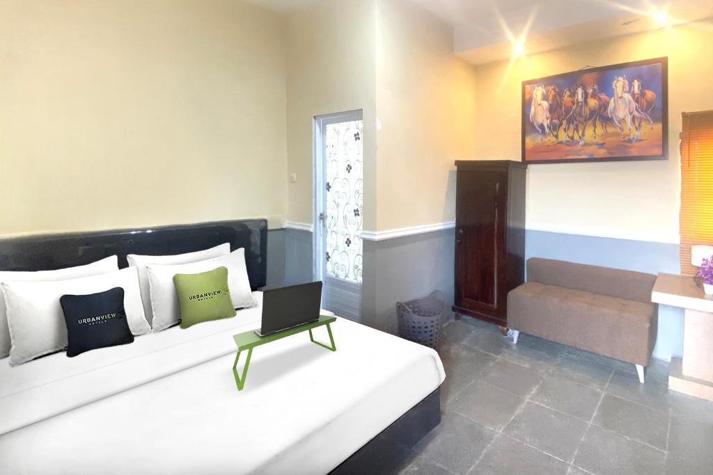 a bedroom with a bed with a laptop on it at Urbanview Hotel Syariah House of Tuwuh by RedDoorz in Tanjungkarang