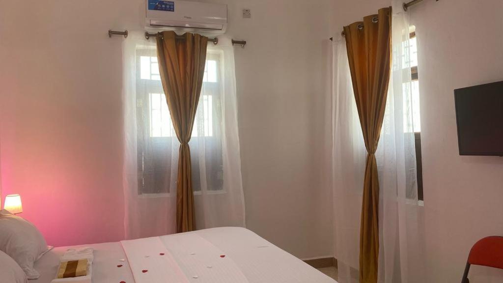 a bedroom with a bed and a window with curtains at African Angel House B&B in Stone Town
