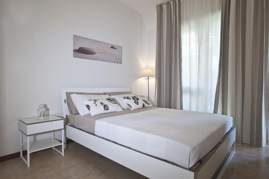 a white bedroom with a bed and a window at Casavacanze Castelli di Sabbia in Porto SantʼElpidio