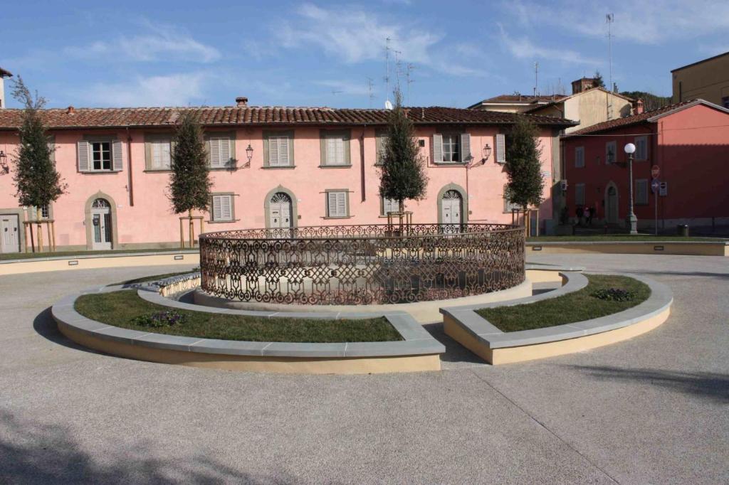 un gran edificio rosa con tres jardines circulares delante de él en Foresteria San Niccolo' 14 en Prato