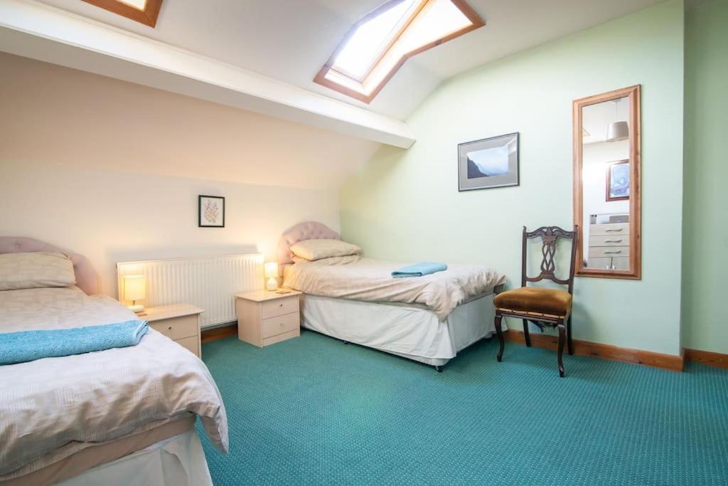 a bedroom with two beds and a mirror and a chair at Midsummer Barn in Darwen