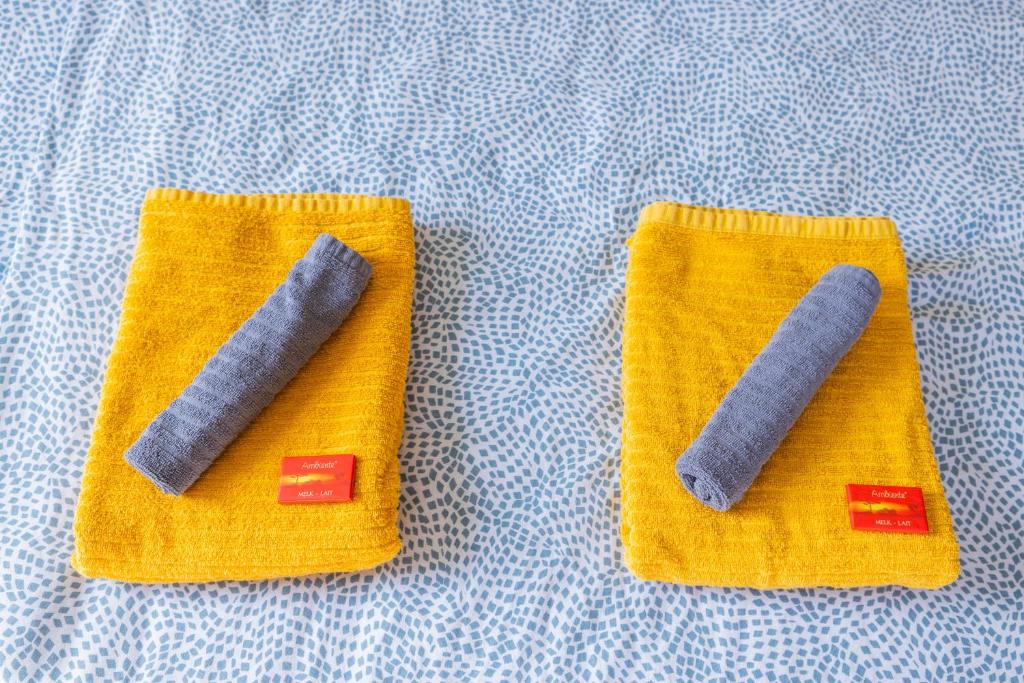 two needle towels with two grey handles on a bed at Good connection Airport & City in Luxembourg