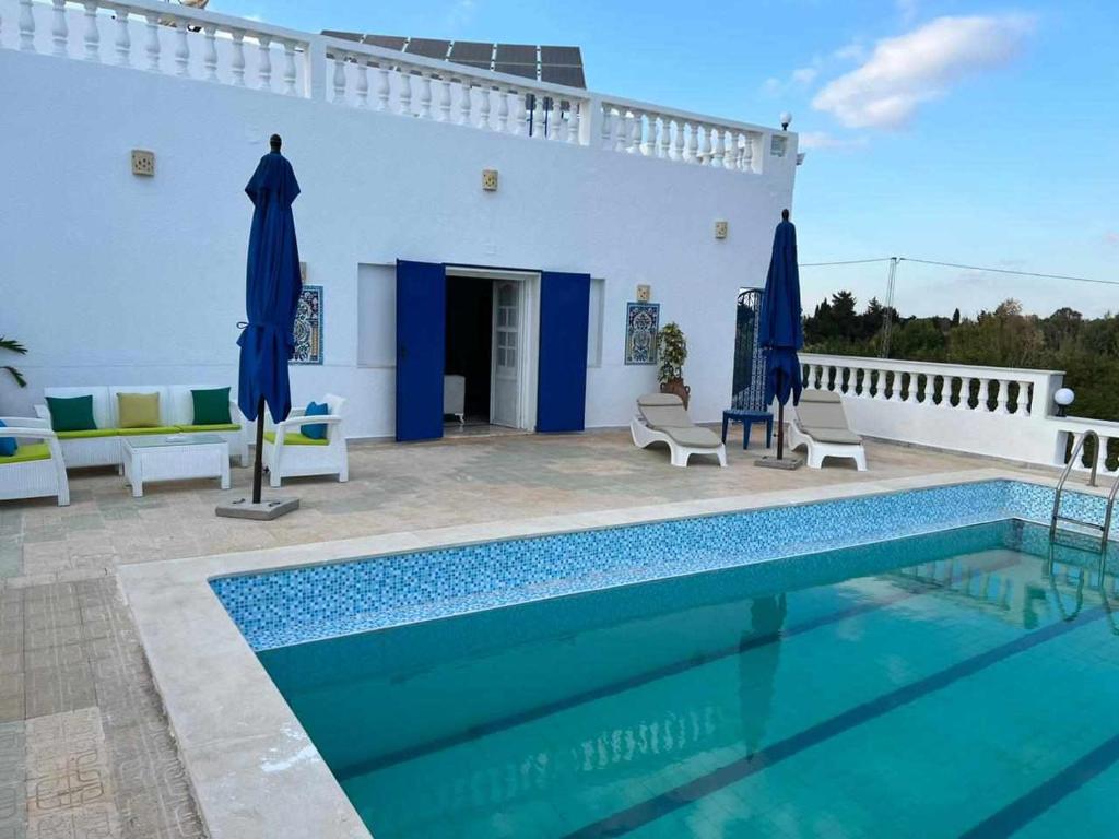 a villa with a swimming pool in front of a house at Dar louzir à Tazarka in Tazarka