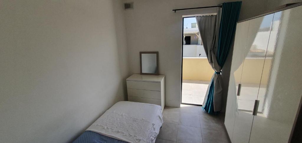 a small bedroom with a bed and a window at A day at Dee's in Birżebbuġa