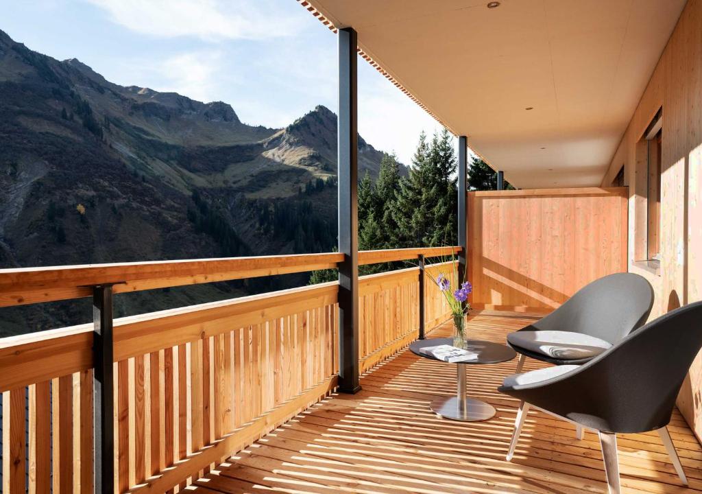 een balkon met 2 stoelen en een tafel en bergen bij Landhaus Damüls in Damuls