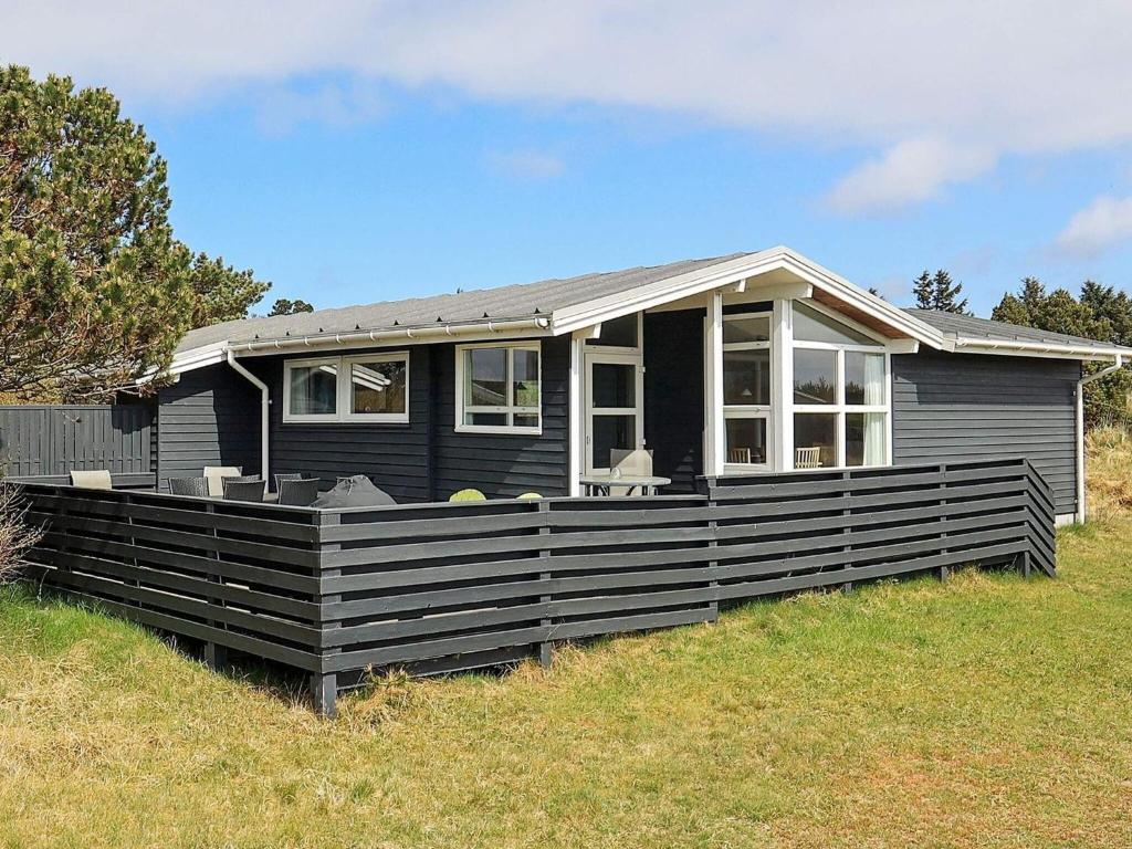 a small black house on top of a field at 6 person holiday home in Vejers Strand in Vejers Strand