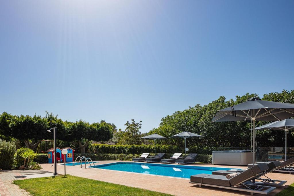 a swimming pool with lounge chairs and umbrellas at Villa Joanna in Prínos