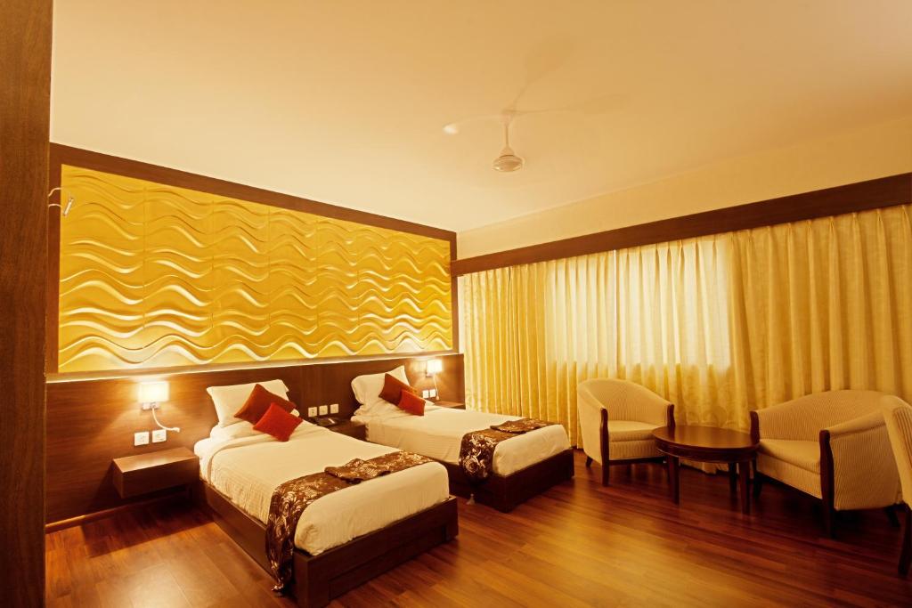 a hotel room with two beds and a table at The Central Park in Rourkela