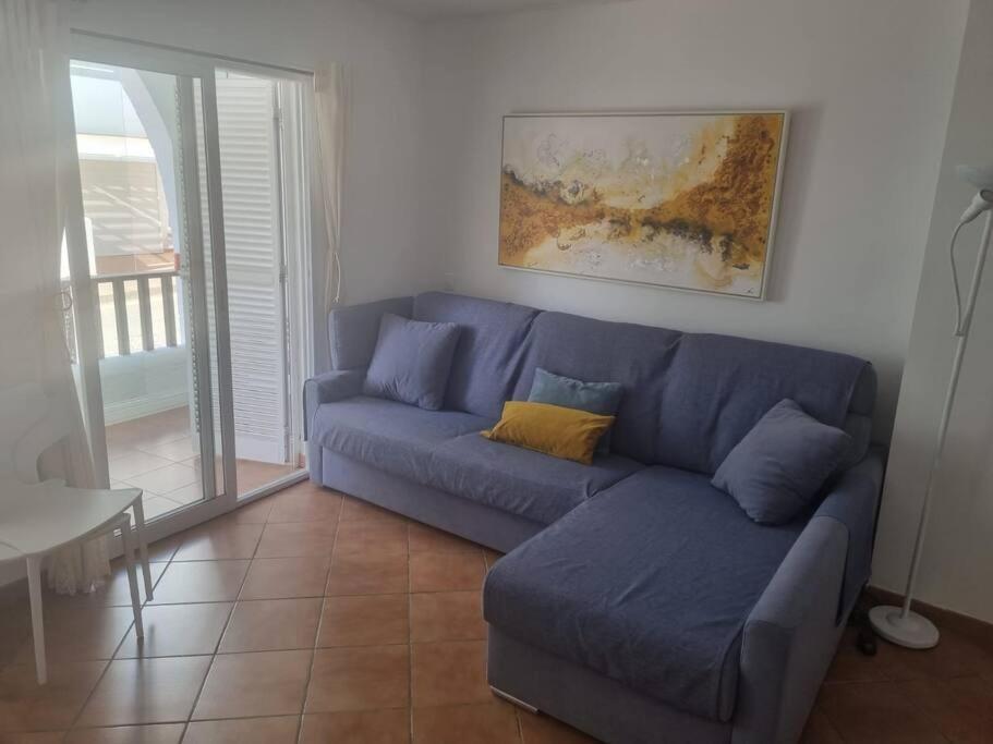 ein blaues Sofa im Wohnzimmer mit einem Tisch in der Unterkunft Apartamento cerca de la playa in Almería