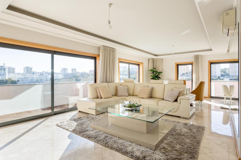 Elegant villa w dual pools in Carnaxide في كارناكسيد: غرفة معيشة مع أريكة بيضاء وطاولة زجاجية