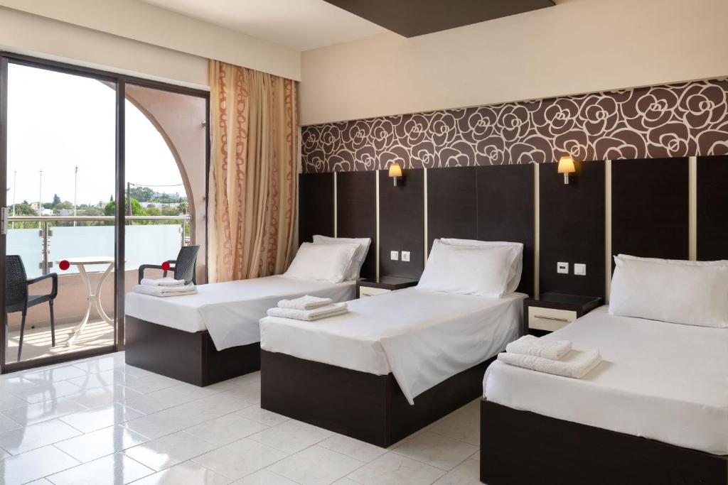 a hotel room with two beds and a balcony at Rose Hotel Faliraki in Faliraki