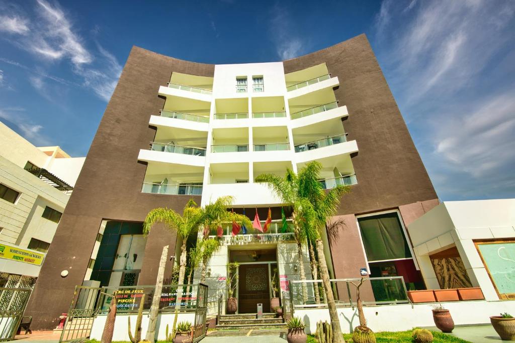 ein hohes Gebäude mit Palmen davor in der Unterkunft Appart Hôtel Founty Beach in Agadir