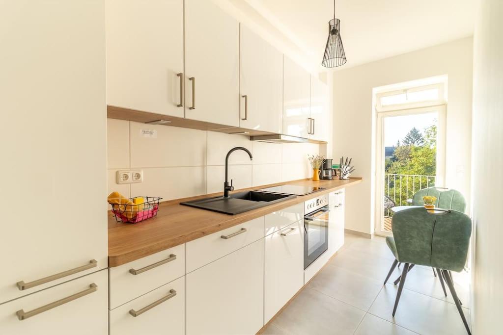 a kitchen with white cabinets and a sink and a chair at *4 Personen, 2 Zi, zentrumsnah* in Pirna