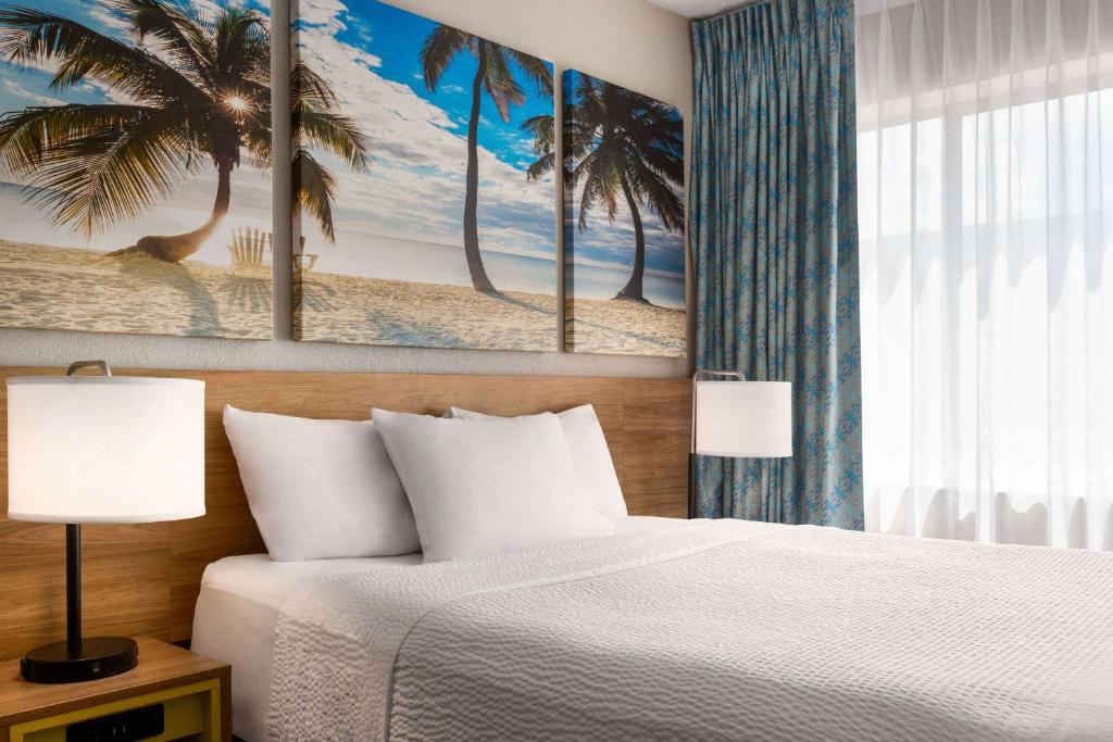 a bedroom with a bed and a palm tree painting at Days Inn by Wyndham Miami Airport North in Miami